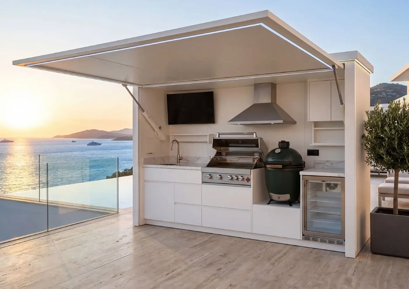 Cuisine d'extérieur Nox Terrace blanche avec abri motorisé ouvert, kamado et barbecue face à la mer